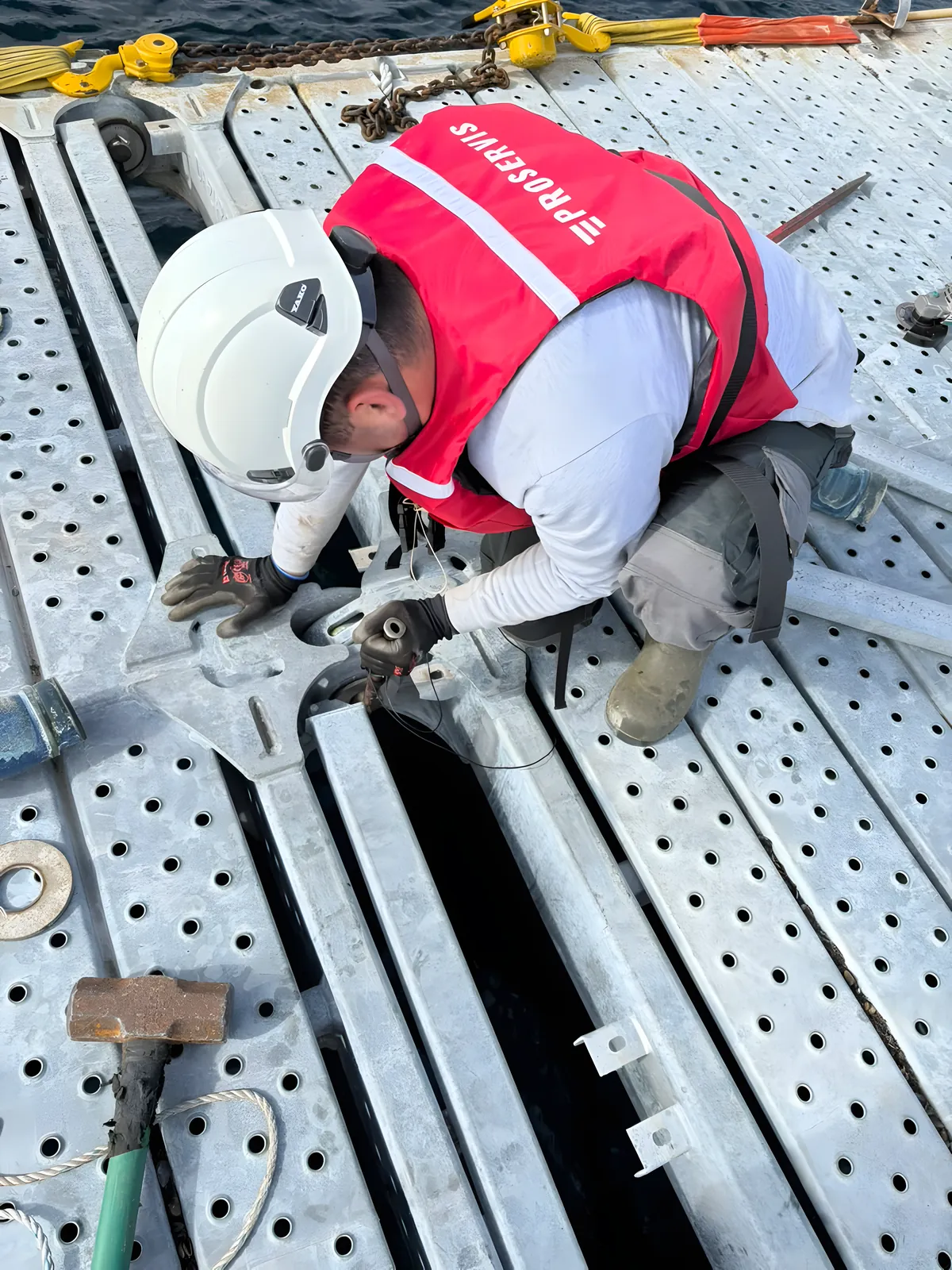 Operario de Proservis con casco y chaleco trabajando en la unión de una estructura flotante